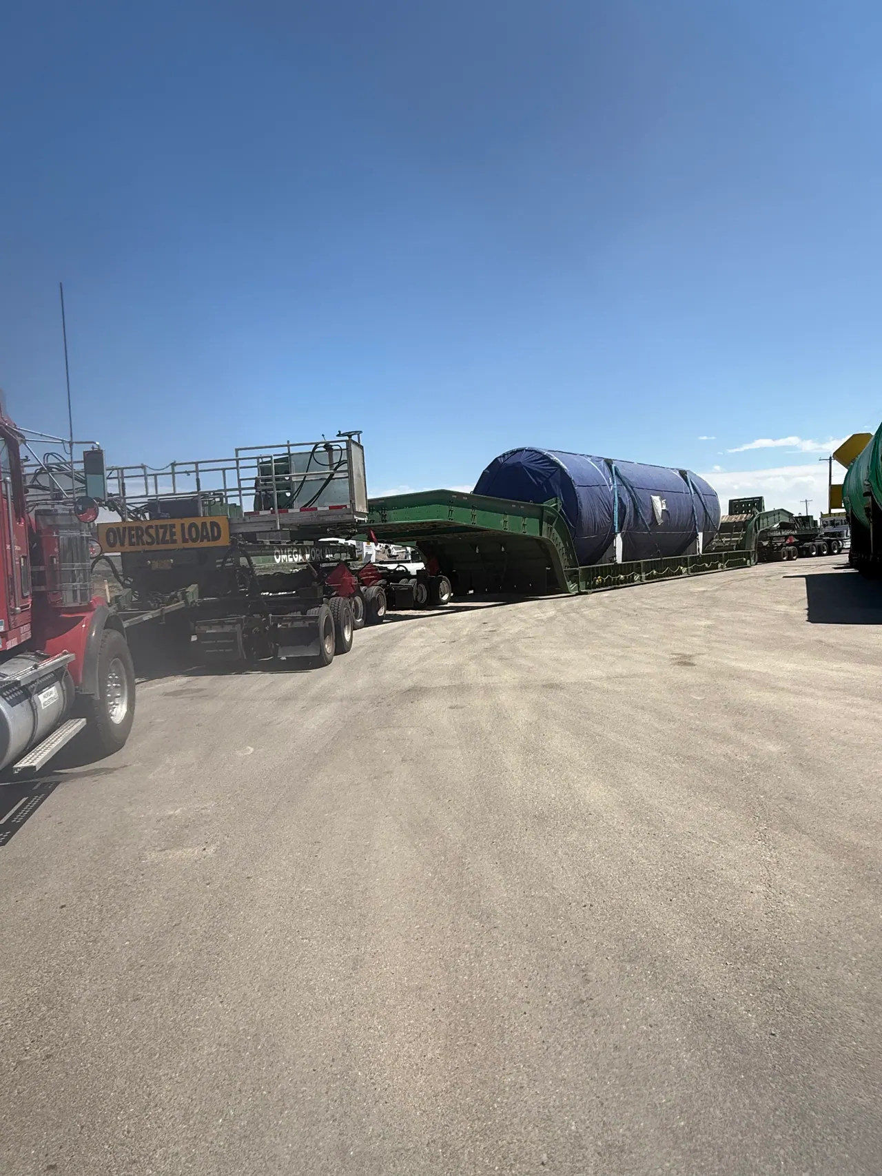 Covered cylindrical equipment secured to a heavy-haul trailer in a staging yard