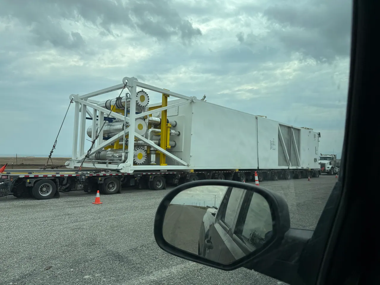 Large industrial assembly on a multi-axle heavy-haul trailer, seen from an escort vehicle